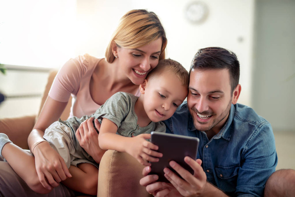 Happy family enjoying together at home, using tablet and having great time together. - 写真・画像