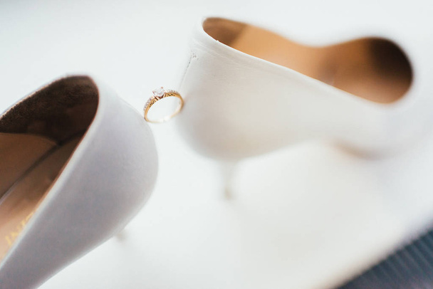 Golden wedding ring between female shoes with heels  - Фото, зображення