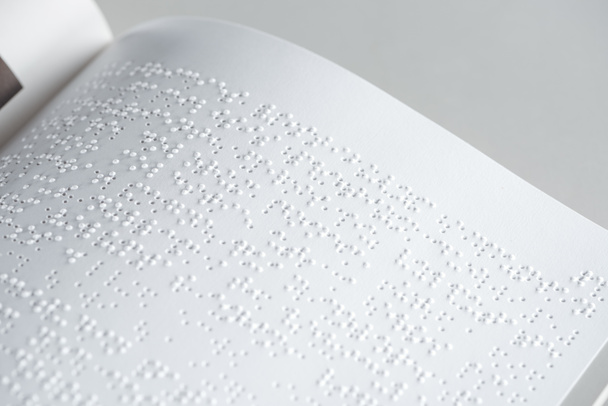 Close-up van braille tekst op wit papier geïsoleerd op grijs - Foto, afbeelding