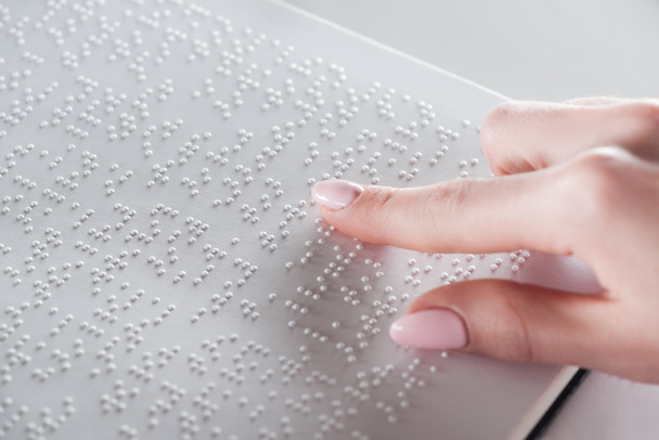 partial view of young woman reading braille text on white paper - Photo, Image