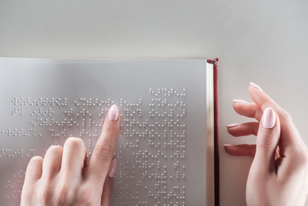 top view of young woman reading braille text on white paper - Фото, зображення