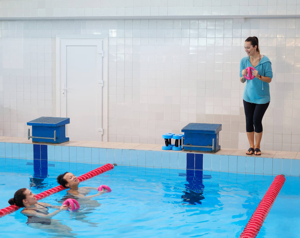 Coppia multirazziale che frequenta un corso di acquagym in piscina
 - Foto, immagini