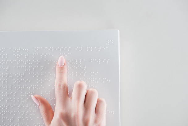 top view of young woman reading braille text on white paper with copy space - Foto, Imagen