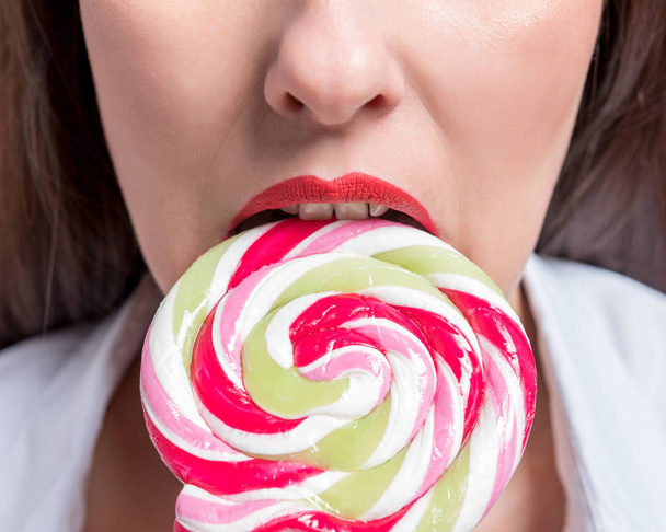 Cropped image of seductive girl biting colorful lollipop.  - Photo, Image
