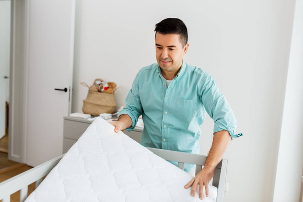 father arranging baby bed with mattress at home - Foto, Imagem