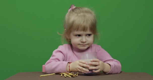 The child eats cookies. A little girl is eating cookies sitting on the table. - Séquence, vidéo