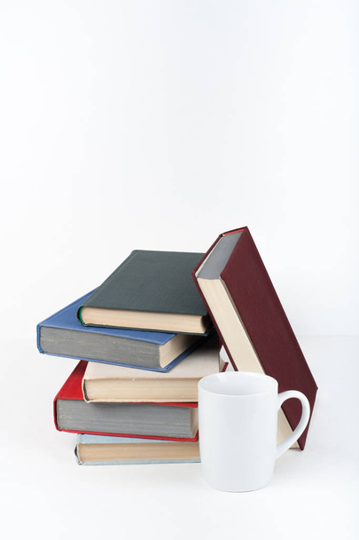 Open book, hardback colorful books on wooden table, white background. Back to school. Cup. Copy space for text. Education business concept - Photo, image