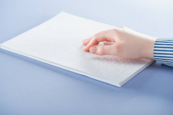 oříznutý pohled mladé ženy čtení Braillova písma textu rukou izolované na fialové - Fotografie, Obrázek