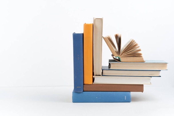 Open book, hardback colorful books on wooden table, white background. Back to school. Copy space for text. Education business concept - Φωτογραφία, εικόνα