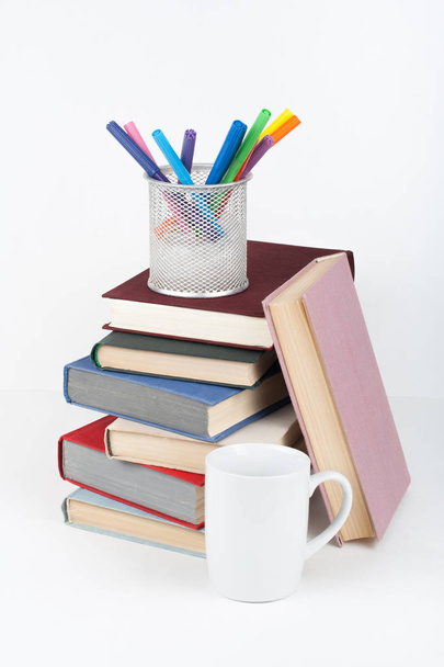 Open book, hardback colorful books on wooden table, white background. Back to school. Pens, pencils, cup. Copy space for text. Education business concept - Фото, изображение
