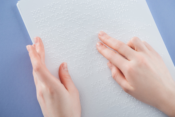 partial view of young woman reading braille text with hand isolated on violet - Foto, immagini