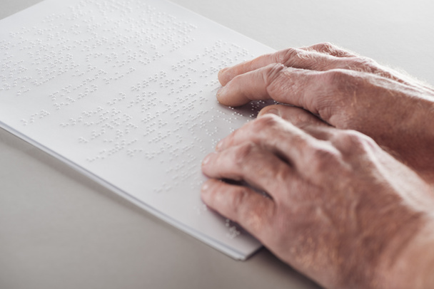 visão cortada do homem sênior lendo texto braille isolado em cinza
 - Foto, Imagem