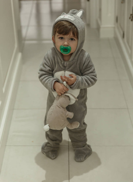 ein niedliches Kleinkind mit einem sehr lustigen Pyjama und einem Schnuller, geht tun - Foto, Bild