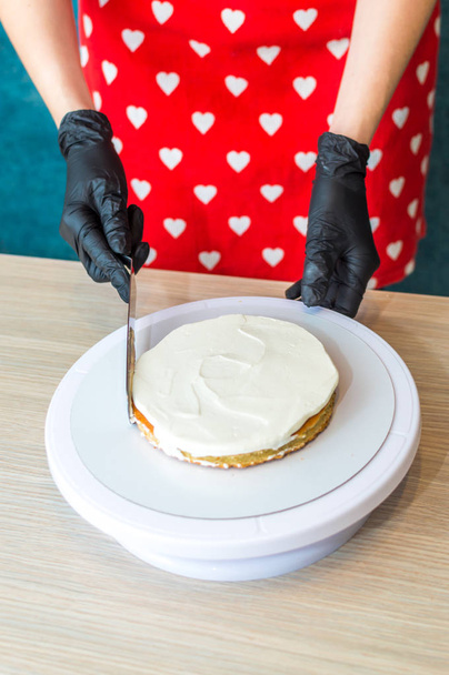 pastry chef puts cream on a sponge cake. Cake making process. Vertical photo - Foto, Imagen