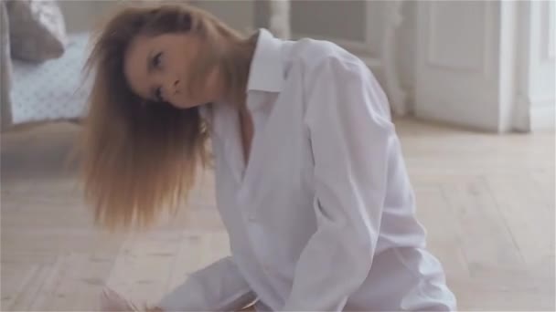 A beautiful young woman in a white shirt is sitting on the floor in the great hall. - Metraje, vídeo