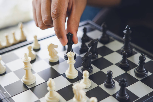 Empresário segurando um Rei Xadrez é colocado em um tabuleiro de xadrez.
 - Foto, Imagem