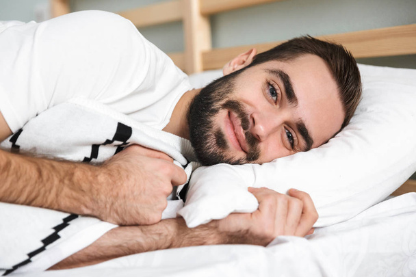 Handsonme usmívající se muž spí na polštáři - Fotografie, Obrázek