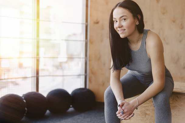 young girl in sportswear in a gym in a simple background, a theme of fitness, and sport - Photo, image