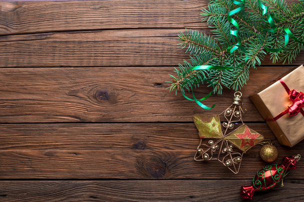 Weihnachtsrahmen aus dekorativem Tannenzweig mit Geschenkschachtel und Ornamenten auf Holzgrund - Foto, Bild