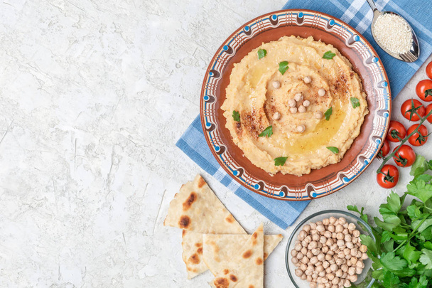 Traditional hummus dish in plate on table with chickpea and vegetables - Foto, Bild