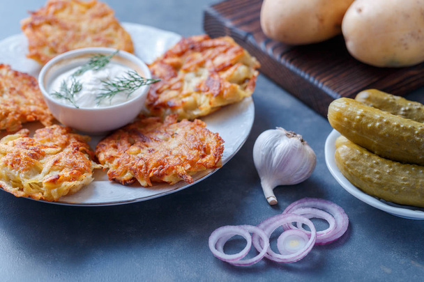 Potato pancakes dish on plate with sour cream and vegetables - Фото, зображення