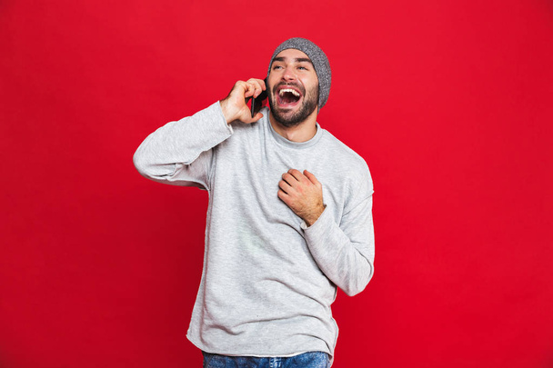 Image of stylish man laughing while using cell phone isolated ov - Zdjęcie, obraz