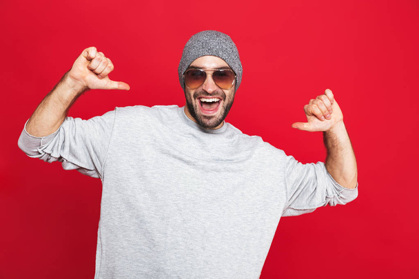 Image of positive man 30s in sunglasses laughing and pointing fi - Фото, зображення