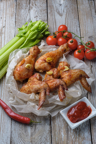 Asas de frango assadas na mesa com molho e legumes
 - Foto, Imagem
