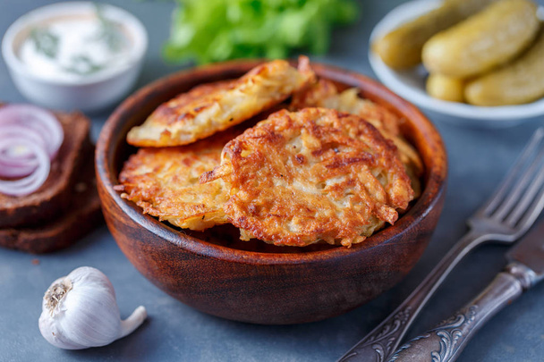 Bowl of potato pancakes with sour cream and pickles - Foto, Imagen