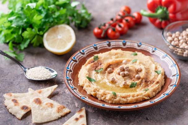 Traditional hummus dish in plate on table with vegetables - Foto, imagen