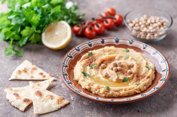 Traditional hummus dish in plate on table with vegetables - Fotoğraf, Görsel