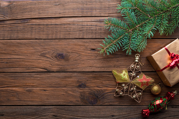 Holiday frame of Christmas decorative fir branch with present box and ornaments on wooden background - Photo, image