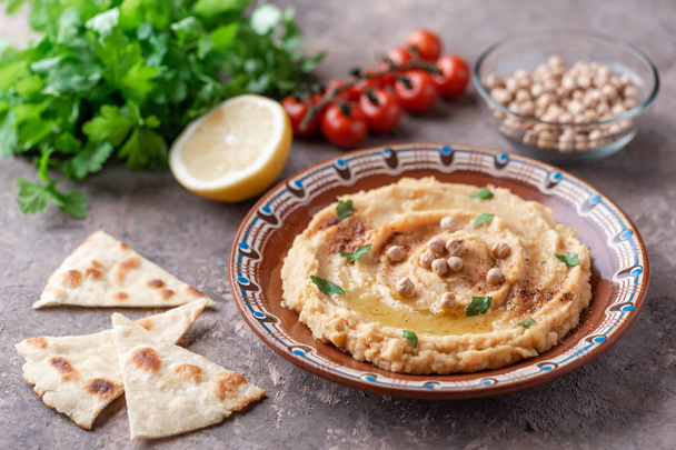 Traditional hummus dish in plate on table with vegetables - Photo, Image