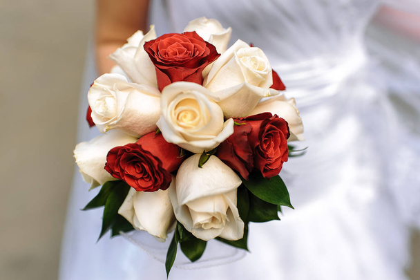 Bridal bouquet of red and white roses in the hand of the bride - Фото, изображение