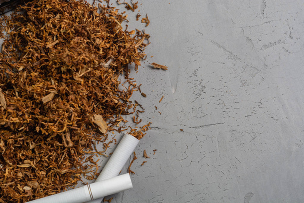 Tabaco picado seco y cigarrillo en el fondo de piedra, copiar el lugar de pasta, vista superior
 - Foto, imagen