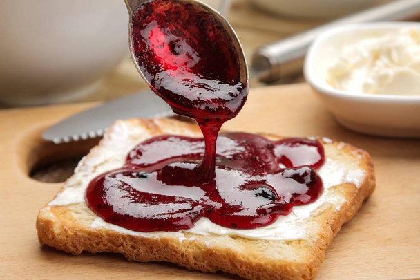 tosty z dżemem. smażone chrupiące tosty z czerwoną jam na naturalnym drewnianym stole. śniadanie. szczelnie-do góry - Zdjęcie, obraz