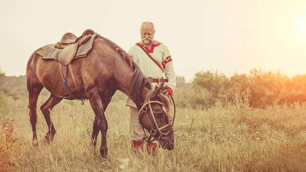 Etnik Giyim erkekte bir at yaz alanlar arka plan üzerinde otlatma. - Fotoğraf, Görsel