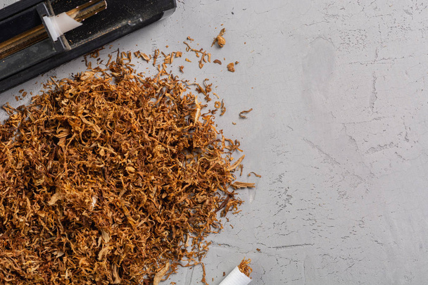Fabrication de cigarettes avec machine à rouler le tabac sur une table en pierre grise, vue du dessus, copier coller place
 - Photo, image