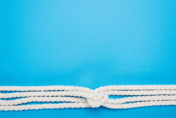 nautical white ropes with sailor knot isolated on blue  - Foto, Bild