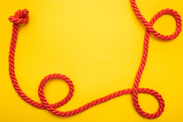 curled and red rope with twisted knot isolated on orange  - Fotoğraf, Görsel