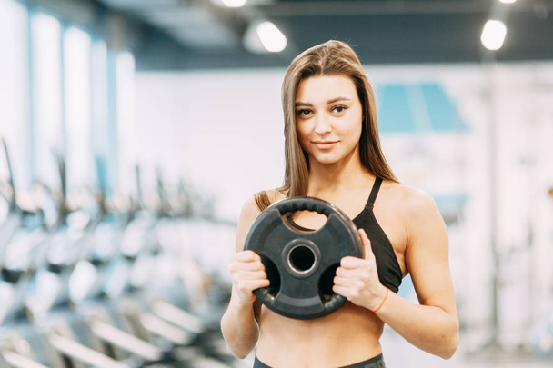 Beautiful girl in the gym. Sports and fitness, healthy lifestyle. - Фото, изображение