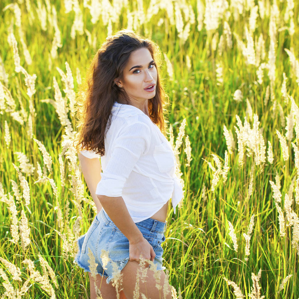 Young beautiful brunette woman in a white shirt and blue denim s - Fotografie, Obrázek