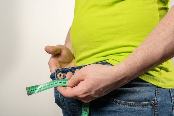 Close up de homem segurando fita métrica perto de jeans com zíper
. - Foto, Imagem