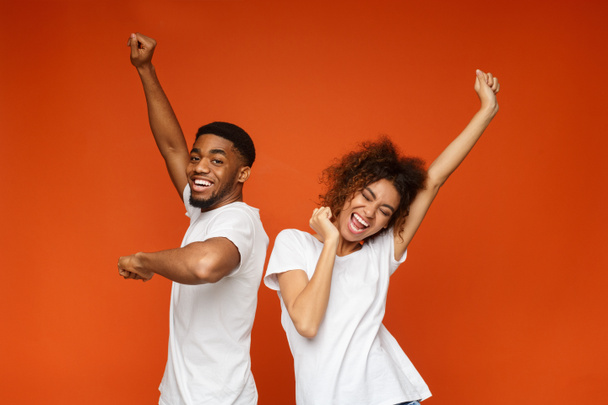 Emotional black man and woman dancing on orange - Fotografie, Obrázek