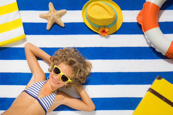 Top view portrait of child on striped beach towel. Summer vacation concept - Foto, afbeelding