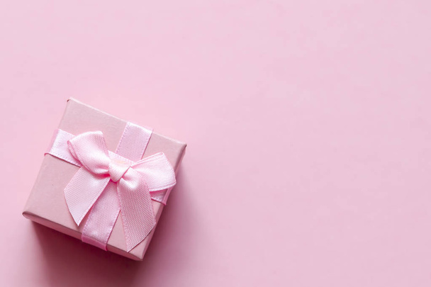 Pink gift box with bow on pink pastel background. Festive backdrop. Top view. Copy space. - Zdjęcie, obraz
