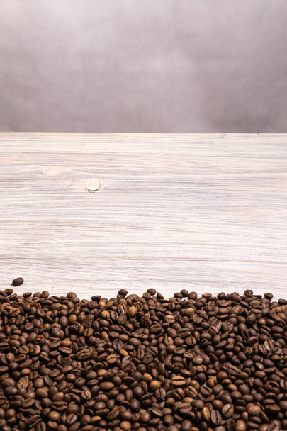 Roasted coffee beans in bulk on a light wooden background. dark  - Photo, Image