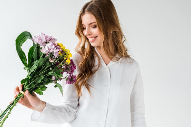 happy girl looking at bouquet of wildflowers on white  - Foto, Bild