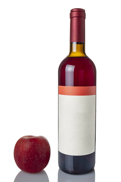 A bottle of red wine with an apple on a white background - Фото, изображение