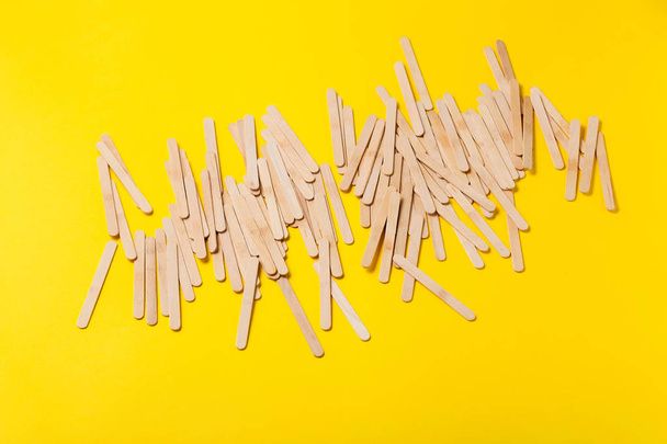 Багато дерев'яних паличок морозива на жовтому фоні
  - Фото, зображення